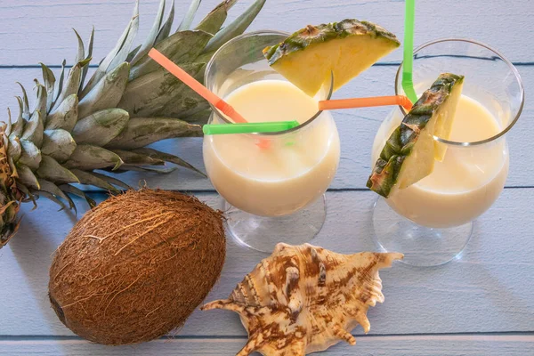 Üzerinde hindistan cevizi ve ananas olan bir masanın üzerindeki bir bardak Pina Colada 'nın manzarası.
