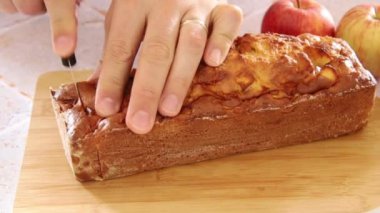 Tahtada kesilmiş bir elmalı pasta kesen biri.