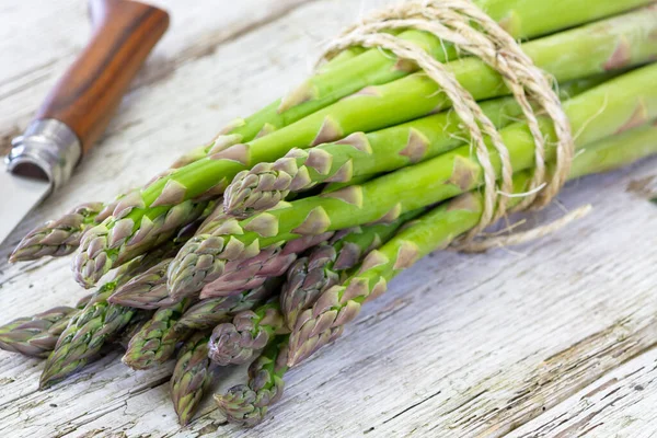 Ahşap arka planda bir sürü taze kuşkonmaz.