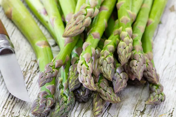 Tahta arka planda taze yeşil kuşkonmaz.