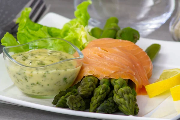 Kuşkonmaz ve beyaz tabakta sos ile nefis somon balığı.