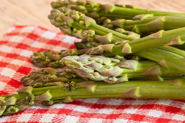 Ahşap masada çiğ yeşil kuşkonmaz.