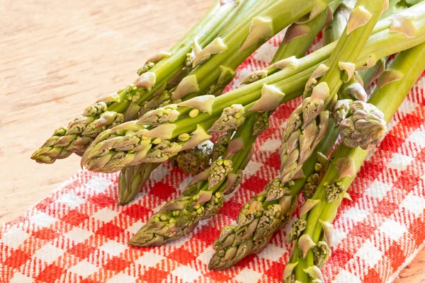 Ahşap masada çiğ yeşil kuşkonmaz.