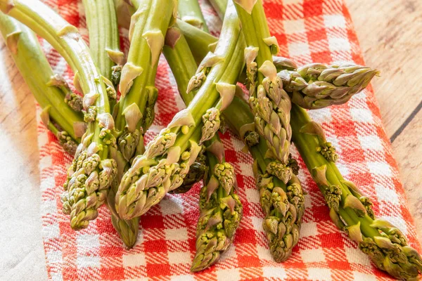 Ahşap masada çiğ yeşil kuşkonmaz.