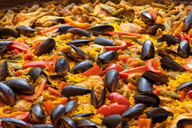 Geleneksel yemeklerinde paella pişiriyor.