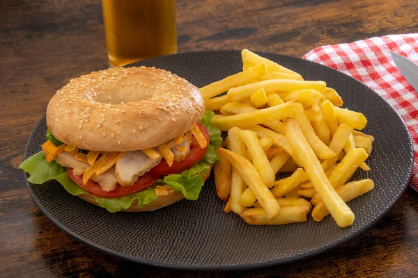 bagel with chicken and fries on a plate