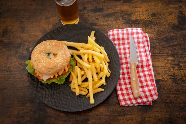 bagel with chicken and fries on a plate