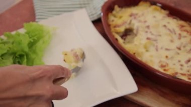 Kadın eli tabakta tartiflette servis yapıyor.