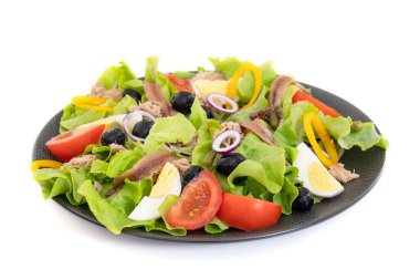 Beyaz arka planda izole edilmiş bir tabak nioise salatası.