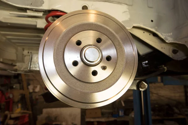 a motor mechanic works on the brake of a car