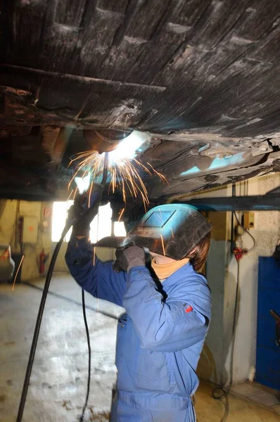 a mechanic welding a car, car repair in a workshop