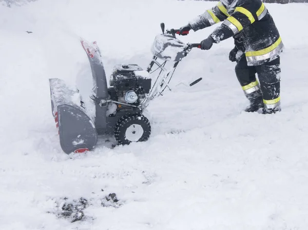 一个吹雪的人正在清扫一条被雪覆盖的道路 — 图库照片