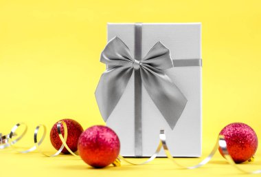 Noel arkaplanı. Hafif hediye kutusu, Noel baloları ve sarı bir arka planda yılan.