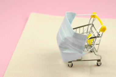 Tıbbi maske takmış alışveriş arabası. Güvenli alışveriş konsepti.