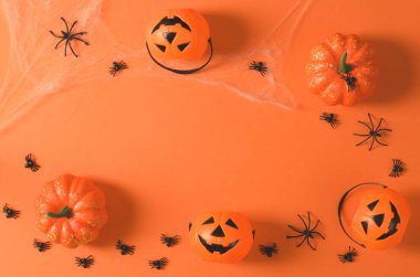 Kabaklar ve örümcekler turuncu arka planda bir ağda, üst görünümde, düz yerde. Turuncu arka planda Cadılar Bayramı için süslemeler, kopyalama alanı. Cadılar Bayramı partisi.