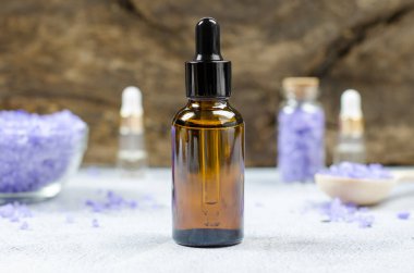 Bir kase deniz tuzu ve yağ şişesinin arka planına karşı bir şişe temel yağ ya da serum. Güzellik spa kompozisyonu.