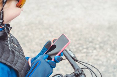 Eldivenli bisikletçi elleri bir akıllı telefon tutar, taklit eder. Akıllı telefondaki haritaları kullanarak yön arayan bir gezgin