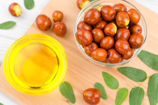 Jojoba yağı ve tahta masada taze kokoba meyvesi.