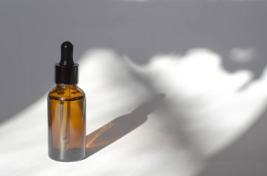 Beyaz arka planda gölgeli kahverengi kozmetik şişesi. Pipetli kozmetik şişesi