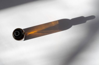 Kahverengi kozmetik şişesinin beyaz arka planda uzun gölgeli görüntüsü. Pipetli kozmetik şişesi