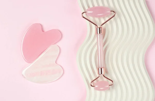 Patenli yeşim yüz masajı aleti. Gua Sha yüz masajı araçları pembe arka planda
