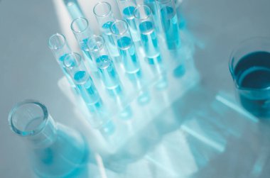 Laboratuvar mataraları ve test tüpleri güneş ışığının altında masanın üzerinde..