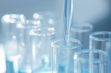 Bilimsel laboratuvar araştırmaları ve deneyleri. Laboratuvar test tüpleri mavi sıvıyla kapanıyor, seçici odaklanma.