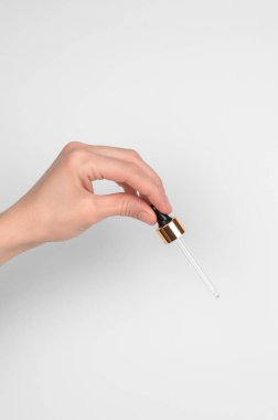 Hafif arka planda bir kadın elinde kozmetik pipeti