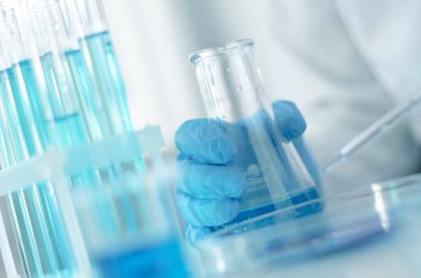 Bilim adamı laboratuarda bir şişe dolusu ayırıcı tutuyor, seçici bir odak. Covid-19 'a karşı çocuklar için bir aşı geliştirilmesi