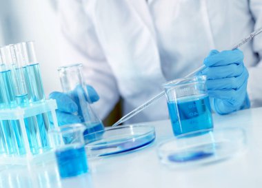 Scientist adds a laboratory pipette liquid to a petri dish, selective focus. Development of a vaccine for children against Covid-19