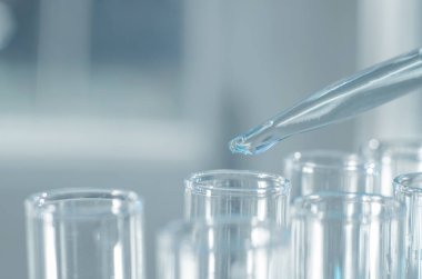 Laboratuvar deney tüpüne damlayan bir laboratuvar pipetinden yakın çekim. Tıbbi araştırma ve geliştirme kavramı