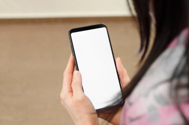 Kadın ellerinde boş beyaz bir ekran olan telefon. Akıllı telefon modeli tutan kadın elleri.