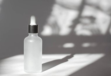 Beyaz arka planda gölgeli, esaslı yağlı beyaz kozmetik şişesi. Kozmetik marka modeli. Cilt bakımı kavramı