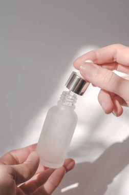 Kadın ellerinde serum olan kozmetik şişesi. Elinde bir şişe gerekli yağ tutan kadın.