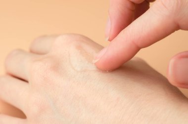 Kadın elinde şeffaf jel. Kadın bileğine nemlendirici jel sürüyor.