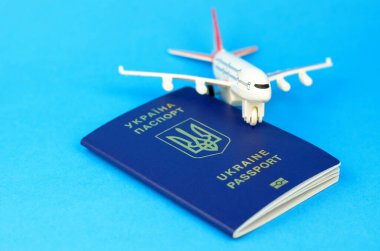 Ukrayna pasaportu ve mavi arka planda oyuncak bir plastik uçak. Ukraynalıların yurt dışına çıkışı