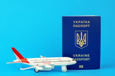 Ukraynalıların yurt dışına çıkışı. Mavi arka planda Ukrayna pasaportu ve oyuncak plastik uçak, seçici odak