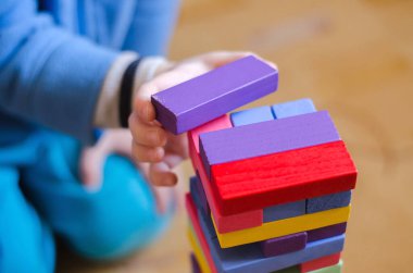 Bir çocuk ahşap renkli blok Jenga oynuyor, yakın plan, seçici odaklanma