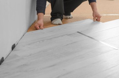 Profesyonel kaplamaları var. Apartmanda tamirat var. Tanımlanamayan adam döşeme kaplaması döşüyor..