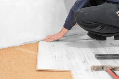 Profesyonel kaplamaları var. Apartmanda tamirat var. Tanımlanamayan adam döşeme kaplaması döşüyor..