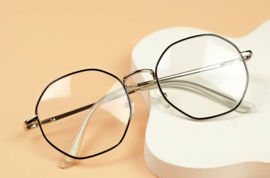 Bej arka planda siyah çerçeveli şık kadın gözlükleri.