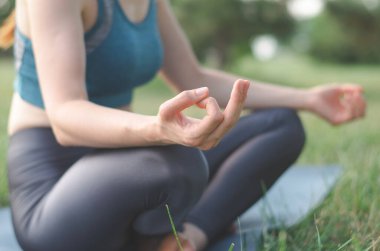 Yoga pozunda oturan tanınmayan orta yaşlı kadın. Parkta meditasyon yapan bir kadın. Tanımlanamayan bir kadın parkta yoga yapıyor, elleri kapalı.
