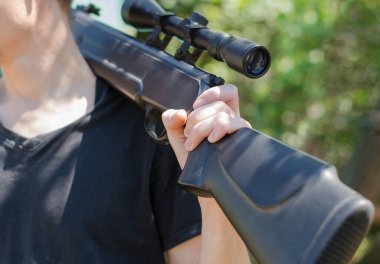 Tanınmayan bir adam omzunda optik görüş olan bir tüfek tutuyor. Bir adamın omzunda pnömatik silah