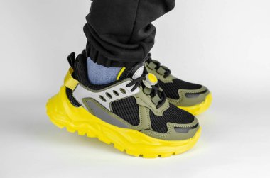 Beyaz arka planda şık ayakkabılar giymiş çocuk ayakları. Haki çocuk ayakkabıları.