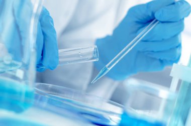 Laboratuvar pipetli bir bilim adamının elleri. Kimyasal deneyler için ekipman. Laboratuvar araştırması yapan bir bilim adamı.