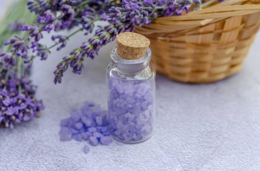 Küçük şeffaf bir şişe içinde lavanta tuzu ve taze lavanta çiçekleri. Spa tedavileri için lavanta tuzu