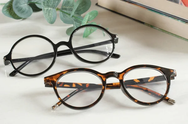 Stylish female glasses on white wooden table