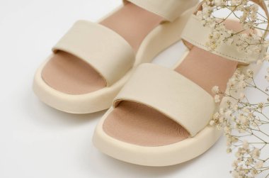Stylish beige women's sandals on a white background, close-up