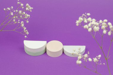 Cosmetic beauty showcase. White round podium for advertising cosmetic products on a purple background with gypsophila bouquets. Empty stand for packing.