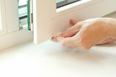 Close-up of male hands installing roller blinds on the window. Installation of roller blinds